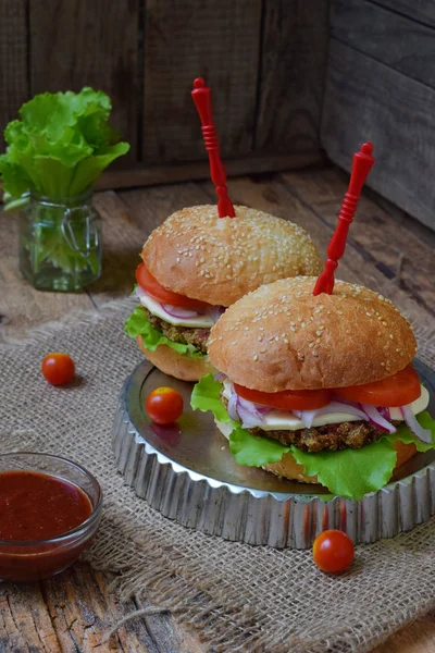 Chop patlıcan, marul, soğan turşusu, domates kahverengi ahşap arka plan üzerinde veggie burger. Vejetaryen öğle veya akşam yemeği fikir. Sağlıklı gıda.