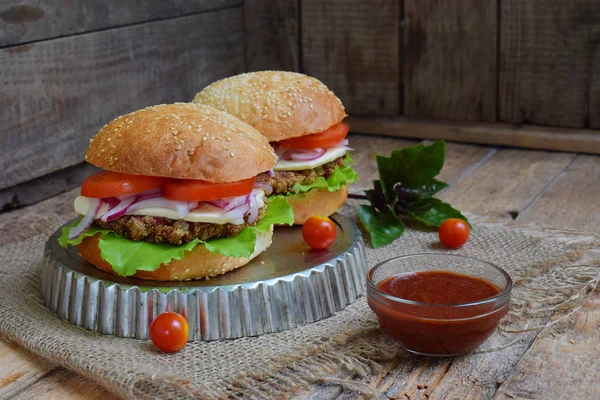 Chop patlıcan, marul, soğan turşusu, domates kahverengi ahşap arka plan üzerinde veggie burger. Vejetaryen öğle veya akşam yemeği fikir. Sağlıklı gıda.