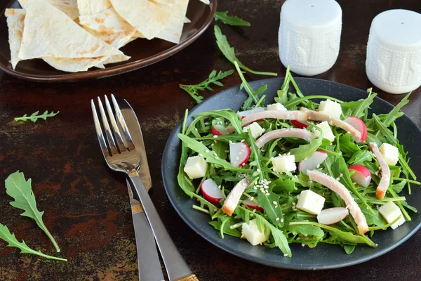 Ensalada de verduras frescas rúcula, rábano, queso feta, jamón y sésamo en plato negro con tortilla de pan plano. Alimento saludable . — Foto de Stock