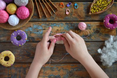 Tığ işi amigurumi çöreği yapıyorum. Bebekler için oyuncak ya da incik boncuk. Masa iplikleri, iğneler, kancalar, pamuk iplikleri. El yapımı bir hediye. Hobiden gelir. DIY el işi konsepti. Adım 1 - tüm detayları örgü.