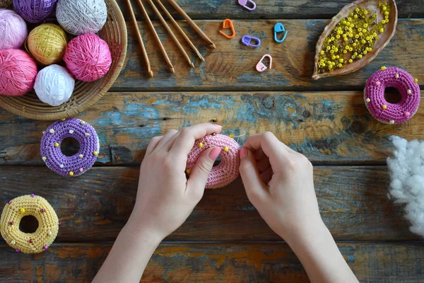 Making crochet amigurumi donuts. The toy for babies or trinket. On the table threads, needles, hook, cotton yarn. Handmade gift. DIY crafts concept. Step 2. Stuff the toy with padding polyester.