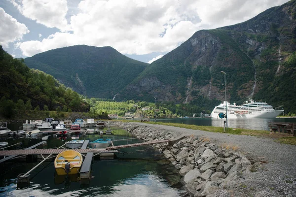 ノルウェーのフラム Aurlandsfj Rden にある雄大な山々の近くに係留されたクルーズ船とボート  — 無料ストックフォト