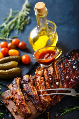 Bir kesme tahtası üzerinde ızgara biftek dilimlenmiş. Ekşili karanlık bir arka plan üzerinde kırmızı biber ve sarımsak ile.