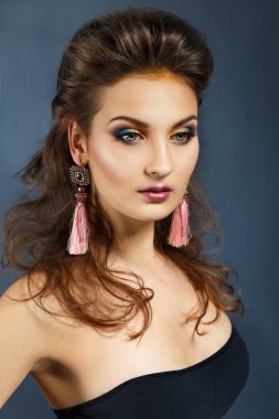 Karanlık bir arka plan üzerinde bir kız güzellik portresi. Uzun küpeler. Akşam makyaj .