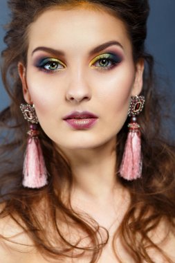 Karanlık bir arka plan üzerinde bir kız güzellik portresi. Uzun küpeler. Akşam makyaj .