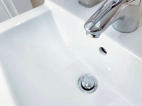 Grifo cromado con palanca para mezclar agua fría y caliente en un moderno lavabo blanco en un baño — Foto de Stock