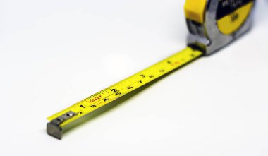 Beyaz arka planda izole edilmiş geri çekilebilir sarı metal mezura. Ölçümler santimetre ve ayakla ifade edilir. Yapılandırma ölçüm aracı