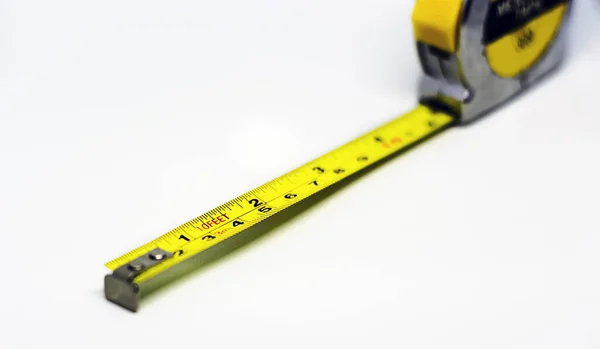 retractable yellow metal measuring tape isolated on a white background. Measurements expressed in centimeters and feet. Construction measuring instrument