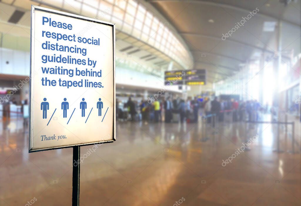 a sign inside an airport warns of the need to maintain the minimum safety distance between people to avoid contagion during the COVID-19 Coronavirus pandemic. Blurred background.  