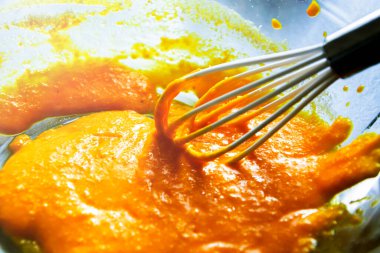 Şeffaf bir kâse içinde kremalı yumurta soslu beyaz bir mutfak çırpıcısı. Carbonara makarna sosu hazırlığı. İtalyan mutfağı tarifi