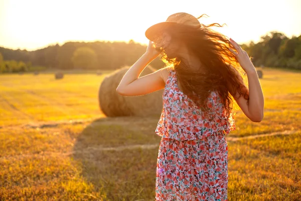 Pretty woman in a hat having fun in stubble field — Stock Photo, Image