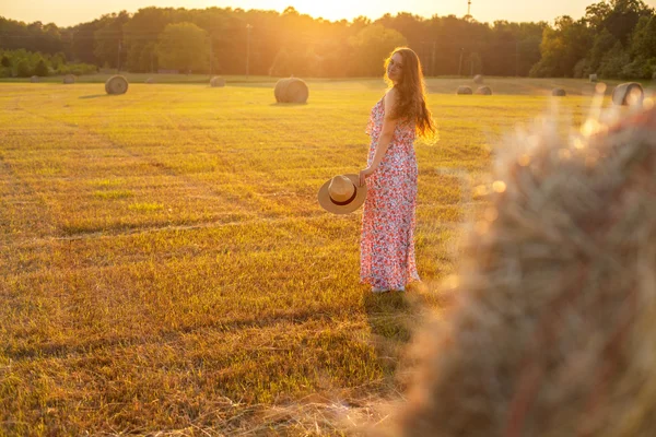 Pretty young woman in hat standing near hay bale — Stock Photo, Image