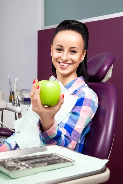 Mulher paciente na cadeira dentária sorrindo com maçã verde — Fotografia de Stock