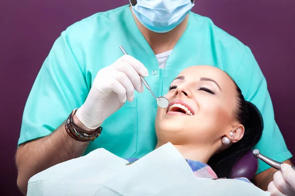 Mulher sentada na cadeira dentária enquanto médico examinando seus dentes — Fotografia de Stock