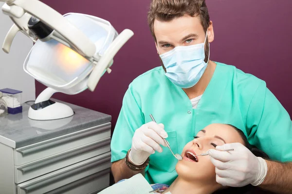 El dentista masculino examina la boca de la mujer en la silla del dentista — Foto de Stock