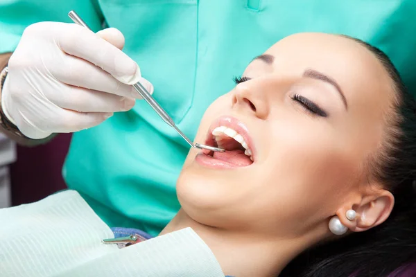 Mujer sentada en silla de dentista mientras el médico examina sus dientes —  Fotos de Stock