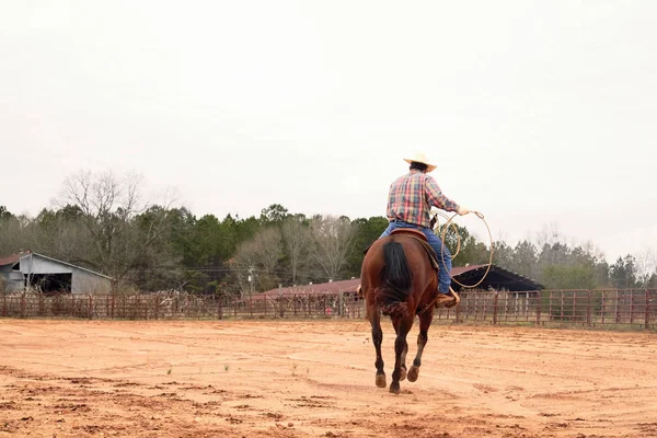 Cowboy montando e galopando a cavalo, jogando laço no rancho — Fotografia de Stock