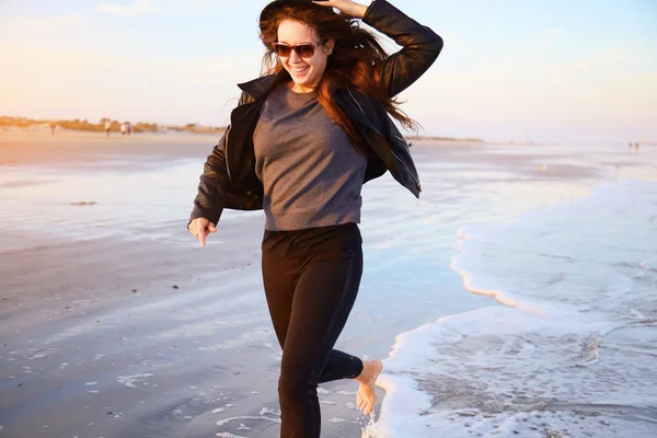 女人开心和运行在海洋海岸的海滩上 免版税图库照片