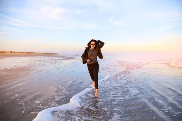 女人开心和运行在海洋海岸的海滩上 图库照片