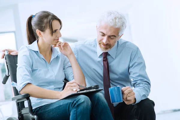 Geschäftsmann zeigt einer Frau im Rollstuhl ein Dokument — Stockfoto