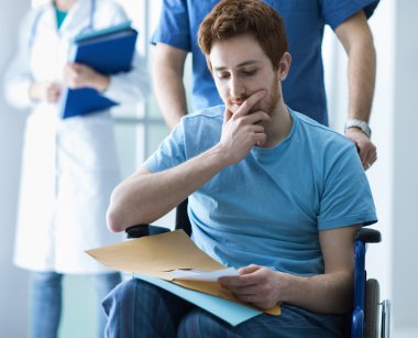 Tekerlekli sandalyede bir adam iterek sağlık işçisi