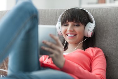 Kadın kulaklıklarla tablet kullanma