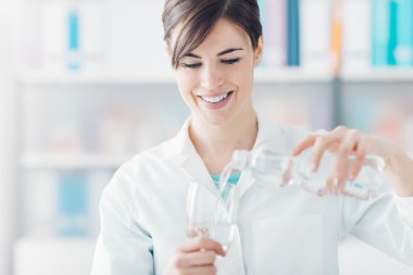 Bir bardak su ve bir şişe tutan doktor