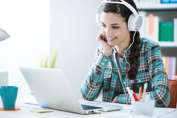 Meisje met hoofdtelefoon met behulp van een laptop — Stockfoto