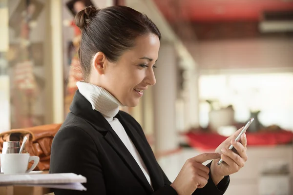 Vrouw aan de balie van texting met haar mobiele telefoon — Stockfoto