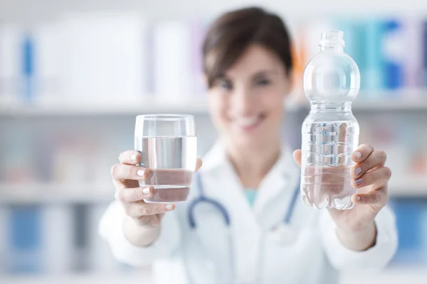 Doctor sosteniendo un vaso de agua y una botella —  Fotos de Stock