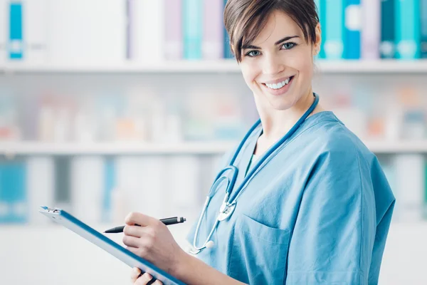 Médico sorridente escrevendo relatórios médicos — Fotografia de Stock