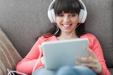 Kadın kulaklıklarla tablet kullanma