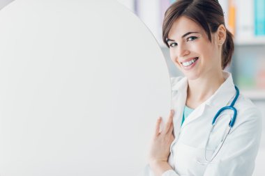 Yuvarlak bir işaret tutan doktor gülümseyen