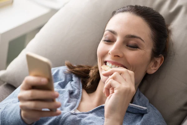 Žena na gauči, pomocí chytrého telefonu — Stock fotografie