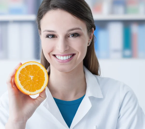 Ernährungsberater hält eine geschnittene Orange in der Hand — Stockfoto