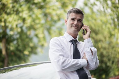 Kendine güvenen Yöneticisi arabasına yaslanmış