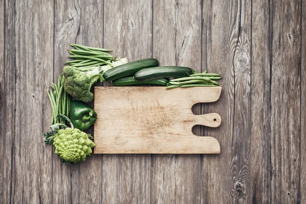 Verduras verdes e tábua de corte rústica — Fotografia de Stock