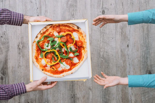 Πίτσα παράδοση στο σπίτι: ένας άνθρωπος είναι παράδοση μια πίτσα σε ένα κουτί σε μια γυναίκα — Φωτογραφία Αρχείου