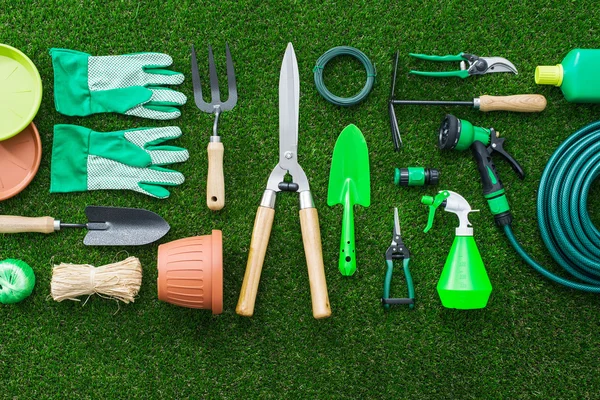 Set di attrezzi da giardinaggio sull'erba lussureggiante in giardino, posa piatta — Foto Stock