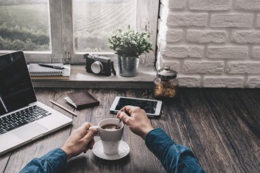 Rahatlatıcı bir sahip hipster adam evde bir pencere yanında Kahvaltı, çay geçiriyor