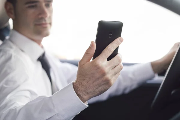 Бизнесмен использует свой смартфон в машине — стоковое фото