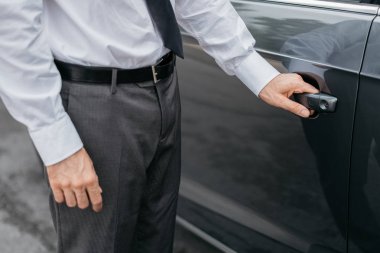 Bir arabanın kapısını açarak iş adamı
