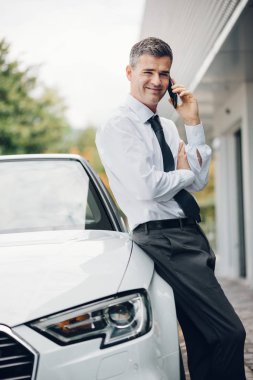 Kendine güvenen Yöneticisi arabasına yaslanmış