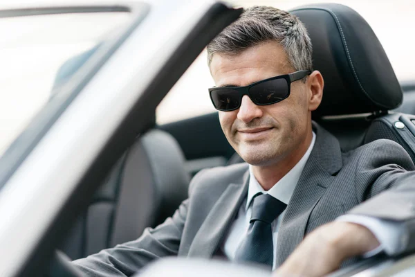 Erfolgreicher selbstbewusster Geschäftsmann sitzt in seinem nagelneuen Cabrio — Stockfoto