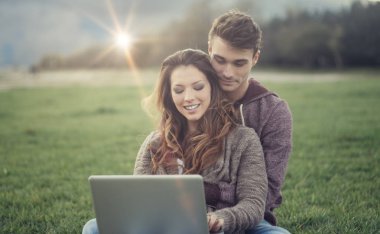 Genç çift açık havada bir dizüstü bilgisayar kullanarak
