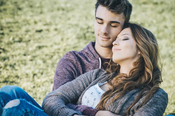 Smiling young couple sitting on the grass — Stock Photo, Image