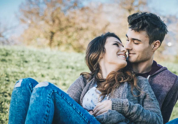 Souriant jeune couple assis sur l'herbe — Photo