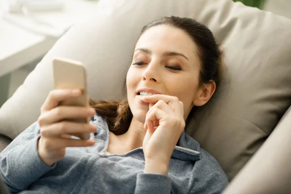 Donna sul divano utilizzando uno smartphone — Foto Stock