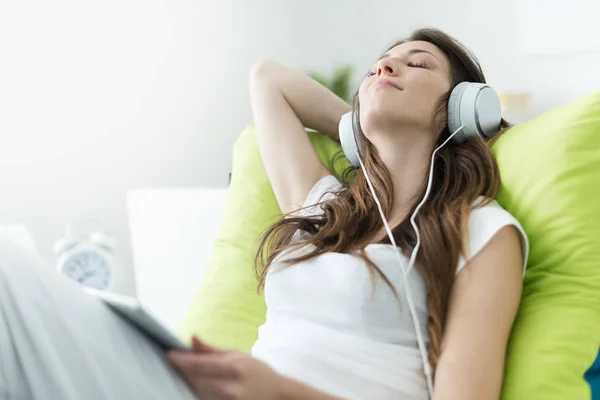 Mooie jonge vrouw met hoofdtelefoon ontspannen op het bed, Chill out — Stockfoto