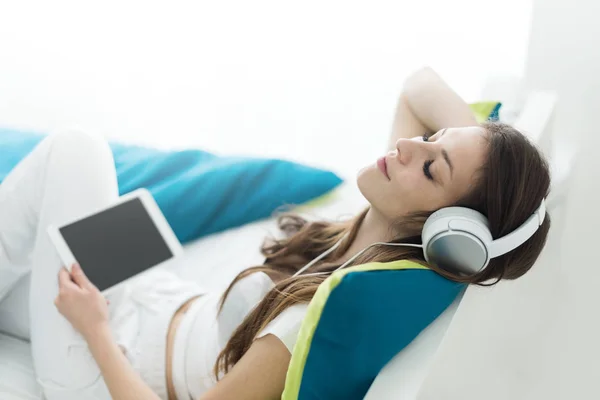 Schöne junge Frau mit Kopfhörern entspannt auf dem Bett, chillen — Stockfoto